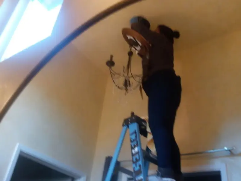 Electrician installing a chandelier in a Harvest residence